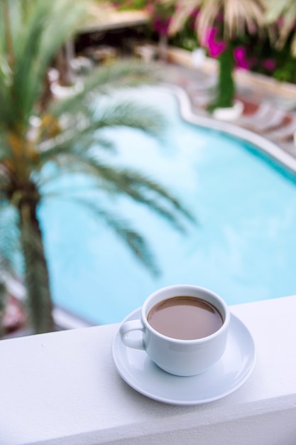 Café com leite em uma xícara branca na varanda do hotel.