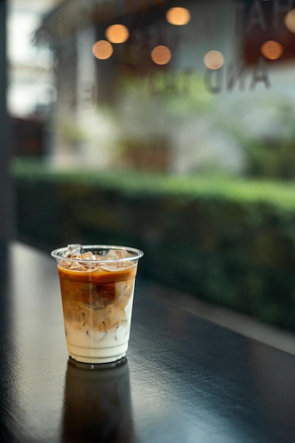 Café com leite gelado em copo de plástico na mesa preta do café