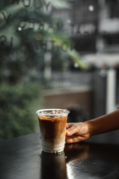 Café com leite gelado em copo de plástico na mesa preta do café