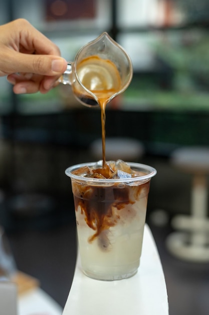 Café com leite gelado em um copo de plástico em uma mesa preta em uma cafeteria