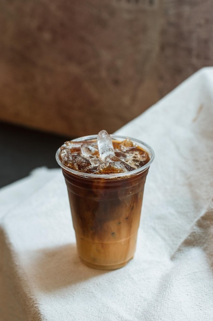 café com leite gelado em vidro plástico na mesa branca no café