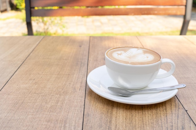 Café com leite ou café cappuccino em xícara branca com arte latte linda árvore na mesa de madeira