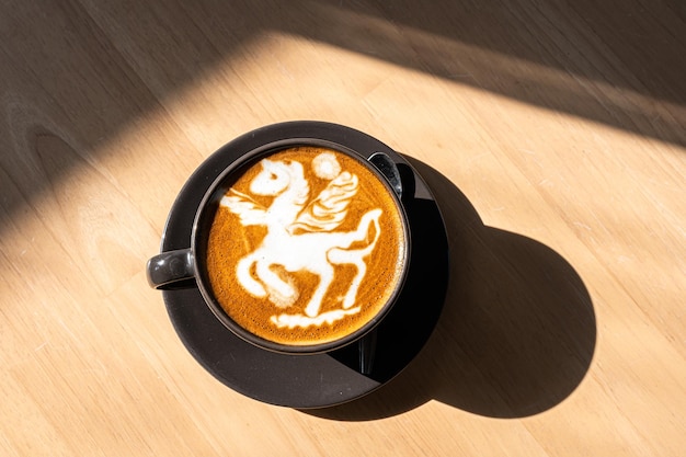 Café com leite quente com arte latte na forma de uma espuma de leite de cavalo na caneca do copo na mesa de madeira na vista superior como café da manhã em uma cafeteria no conceito de trabalho de negócios de café