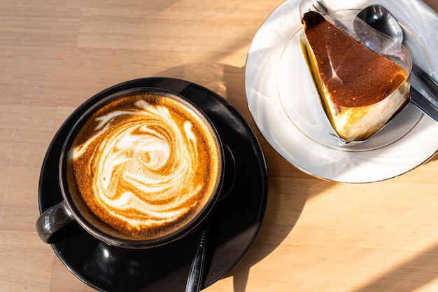 Café com leite quente com espuma de leite latte art na caneca do copo e mesa de madeira de bolo de chocolate caseiro na mesa de madeira na vista superior como café da manhã em uma cafeteria no conceito de trabalho de negócios de café