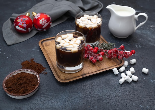 Foto café com marshmallows para dois em uma mesa escura com enfeites de natal