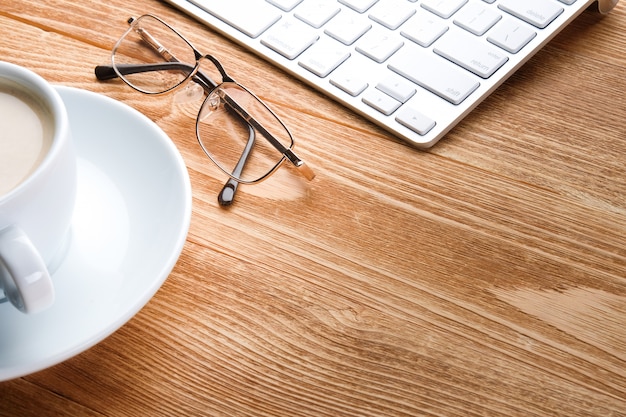 café, computador e óculos em uma mesa de madeira