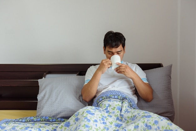 Café de consumición del hombre asiático en tiempo de mañana en casa