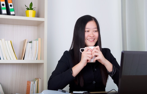 Café de consumición joven hermoso de la mujer de negocios en oficina