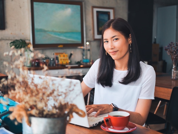 Café de consumición de la mujer asiática en café de la cafetería