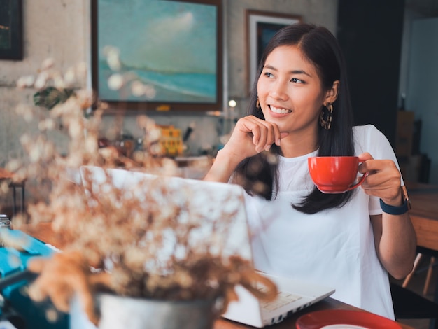 Café de consumición de la mujer asiática en café de la cafetería