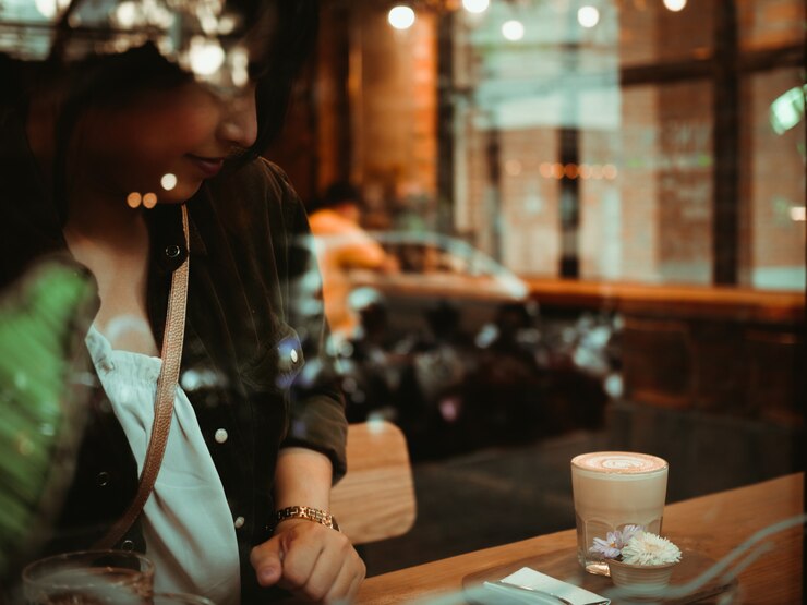 Café de consumición de la mujer asiática en café de la cafetería