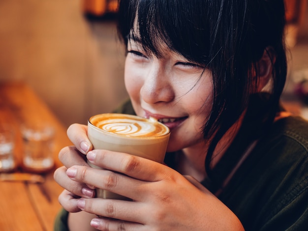 Café de consumición de la mujer asiática en café de la cafetería