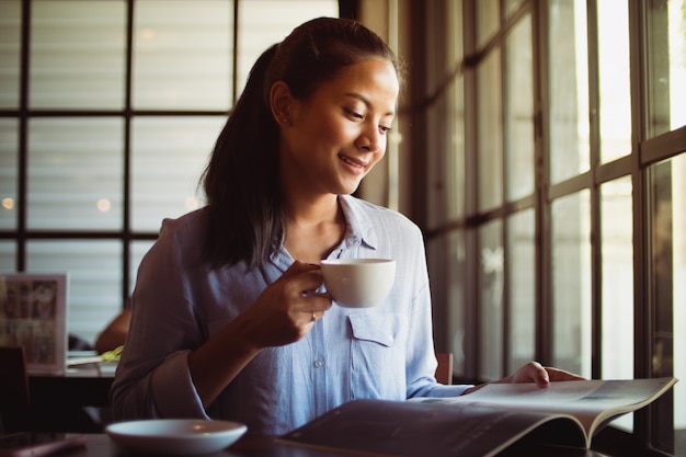 Café de consumición de la mujer asiática en café