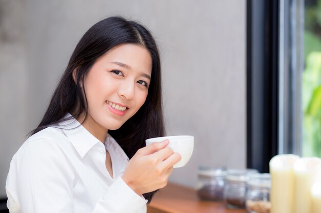 Café de consumición de la mujer asiática hermosa y sonrisa por la mañana en el café.