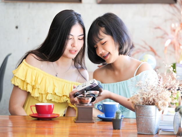 El café de consumición de la mujer asiática y se relaja en café de la cafetería