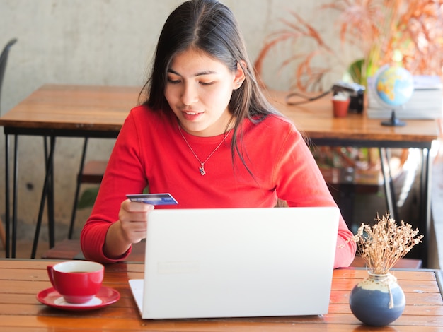 El café de consumición de la mujer asiática y se relaja en café de la cafetería