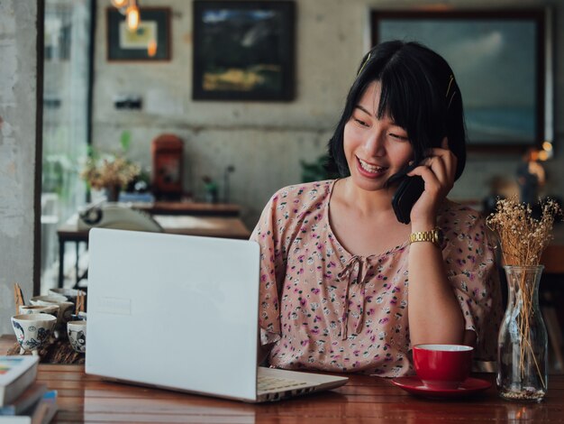 El café de consumición de la mujer asiática y se relaja en café de la cafetería