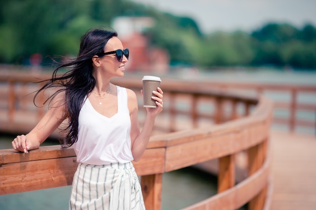 Café de consumición de la mujer urbana joven feliz en ciudad europea.