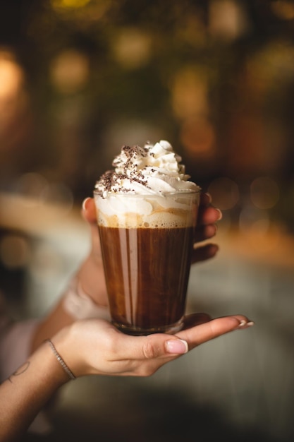 Café con crema batida y chispas de chocolate en manos de una chica