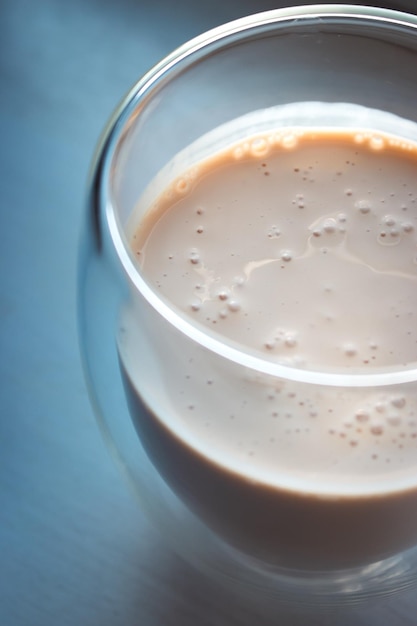 Foto café cremoso em fundo azul espuma de leite com expresso em copo frappe em copo na mesa