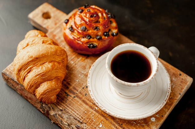 Café y croissant, bollo sobre una mesa de piedra. desayuno de la mañana