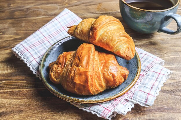 Café y croissant en la mesa de madera rústica. Desayuno francés.