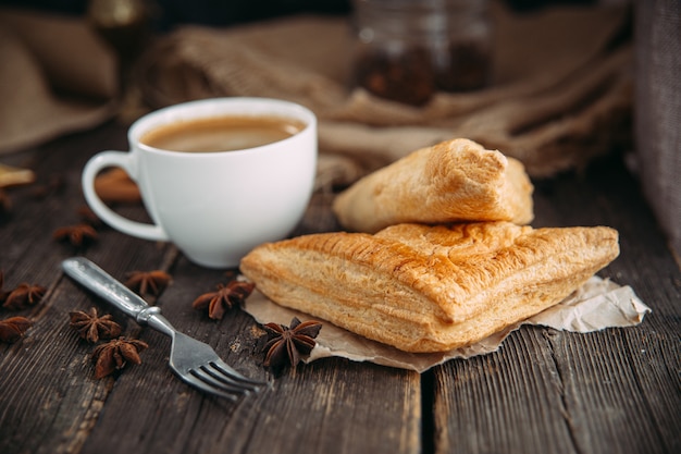 Café y croissant en la mesa de madera.