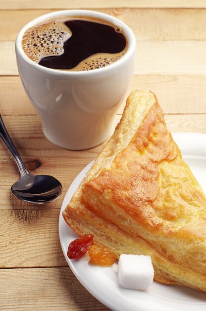 Café y croissant en mesa de madera