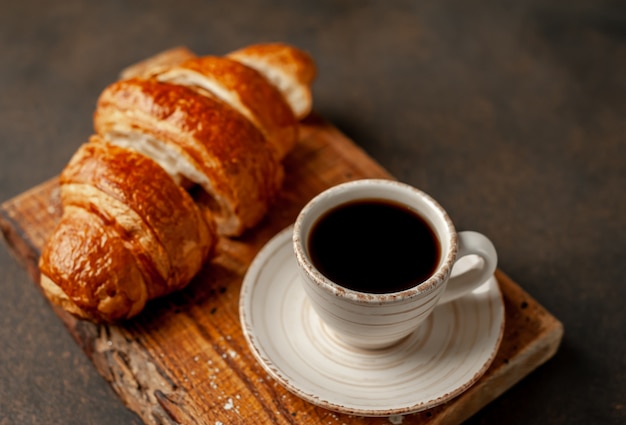 Café y croissant sobre un fondo de piedra. desayuno sabroso