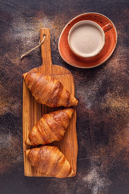 Café y croissant sobre fondo de piedra