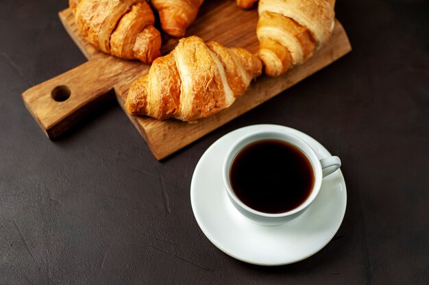 café y cruasanes en tabla de cortar de madera