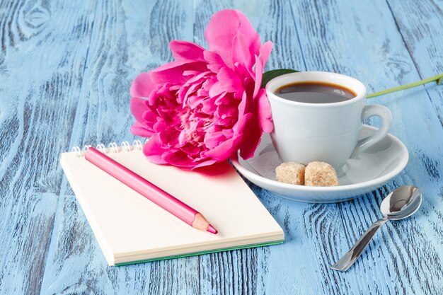 Café con cuaderno y flor de peonía