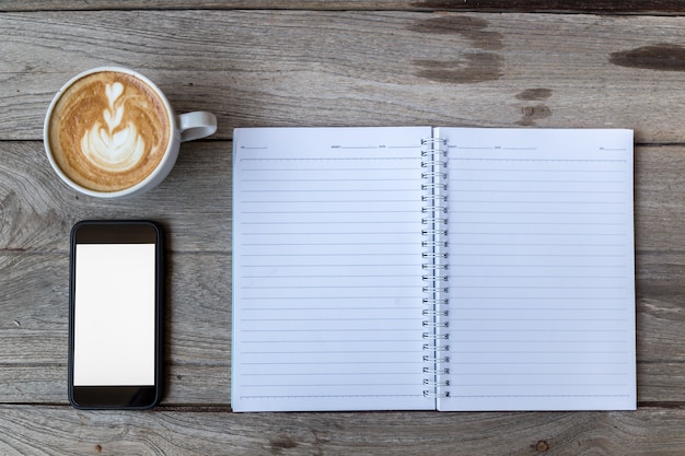 café del cuaderno y teléfono inteligente en la mesa de madera