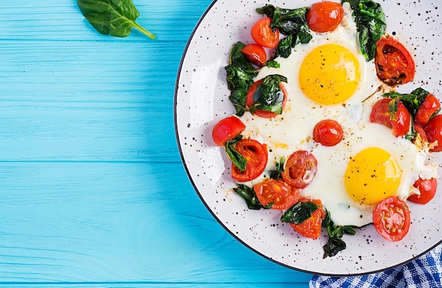 Café da manhã Alimentos de dieta cetogênica Ovos fritos, espinafre e tomates Café da manhã keto paleo Vista superior do espaço de cópia