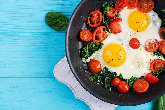 Café da manhã Alimentos de dieta cetogênica Ovos fritos, espinafre e tomates Café da manhã keto paleo Vista superior do espaço de cópia