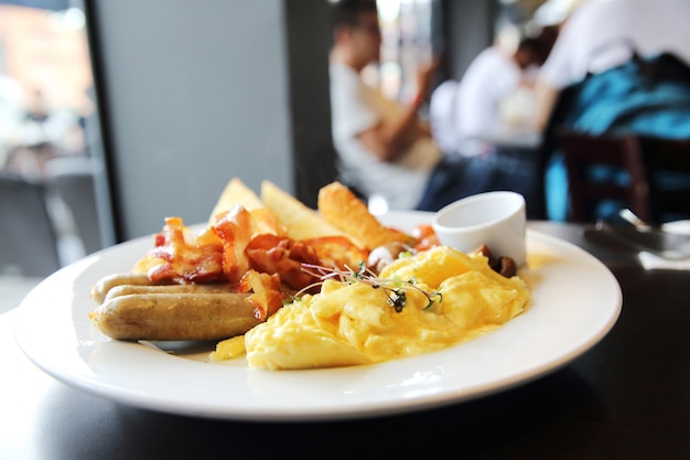 Café da manhã americano com bacon, ovo mexido em fundo de madeira