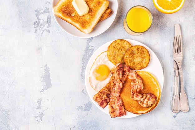 Café da manhã americano completo e saudável com ovos, bacon, panquecas e latkes, vista superior.
