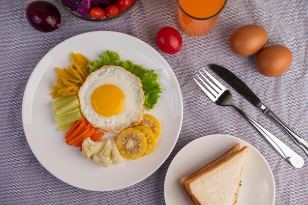 Café da manhã americano em fundo branco com salada de ovos fritos abóbora cenoura cenoura milho couve-flor tomate torrado e suco de laranja