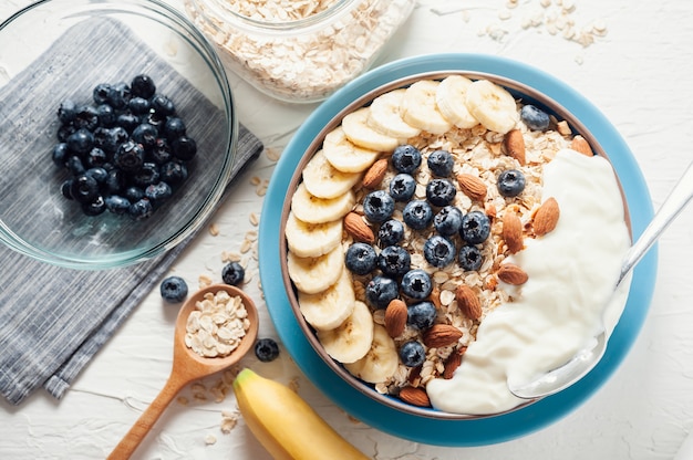 Café da manhã, aveia com mirtilo, banana amêndoa e iogurte em uma tigela de manhã.