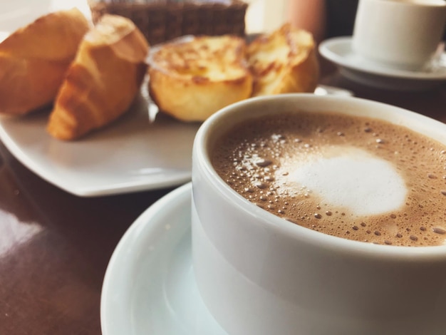 Café da manhã brasileiro. Xícara de capuccino e pão torrado com fundo de manteiga.