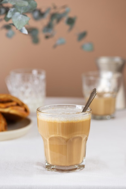 Café da manhã café com leite em um copo com pães de canela na mesa estilo rústico