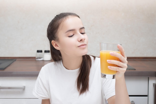 Café da manhã caseiro. A garota está bebendo suco de laranja.