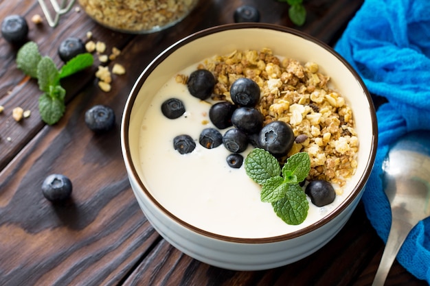 Café da manhã caseiro saudável em uma tigela com granola caseira assada, mirtilo fresco e iogurte