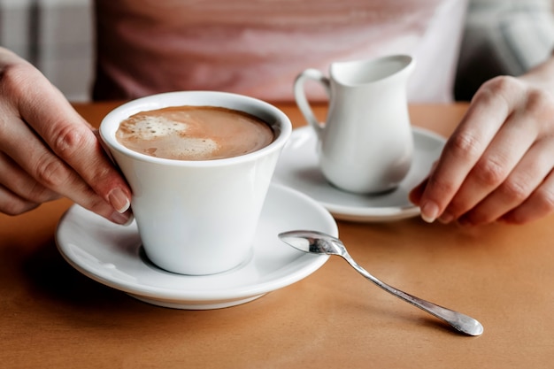 Café da manhã. Close up das mãos das mulheres com copo de café em um café.