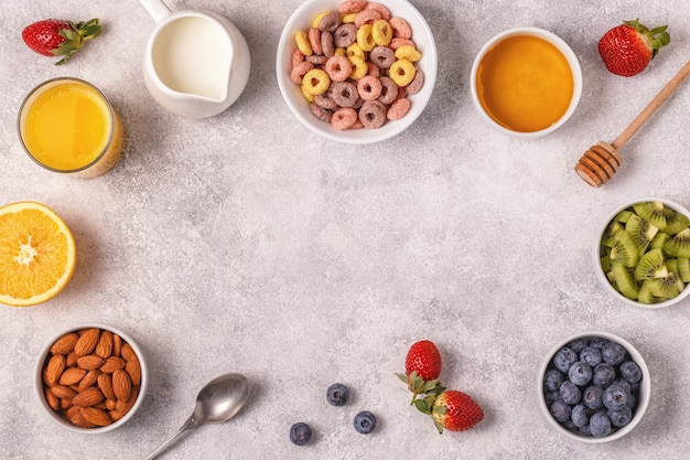 Café da manhã com anéis de cereais coloridos, frutas, leite, suco