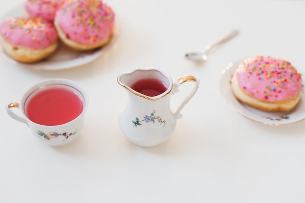 Café da manhã com bebida rosa colorida e rosquinhas na mesa branca composição de festa de aniversário flatlay vista superior