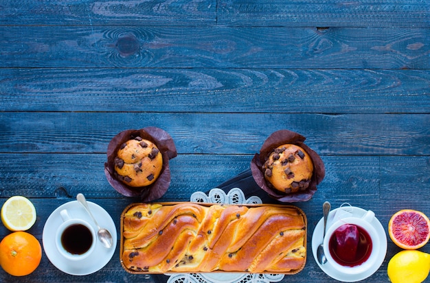 Café da manhã com café e chá com diferentes bolos e frutas em uma mesa de madeira