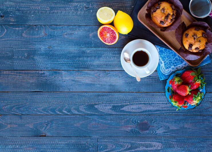 Foto café da manhã com café e chá com diferentes bolos e frutas em uma mesa de madeira