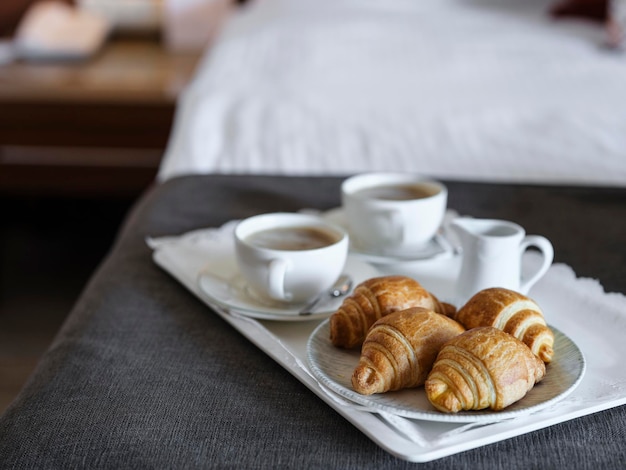 Café da manhã com café e croissant no quarto de hotel