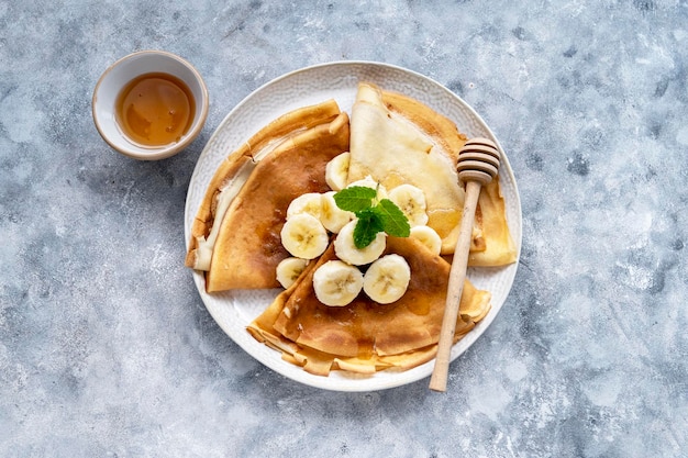 Café da manhã com cepes recém-assados ou panquecas finas, servido com mel e xícara de chá quente